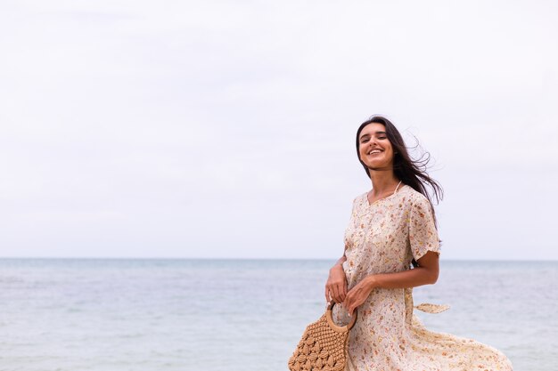 Retrato romântico de mulher em um vestido longo na praia em dia nublado com vento.