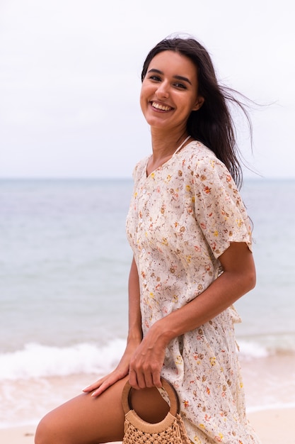 Retrato romântico de mulher em um vestido longo na praia em dia nublado com vento.