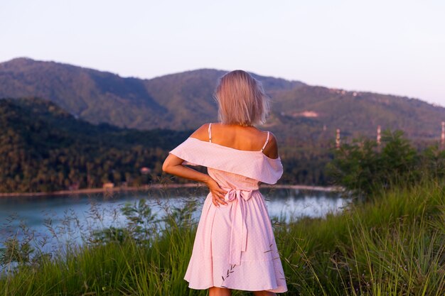 Retrato romântico de uma jovem mulher caucasiana com vestido de verão relaxando no parque na montanha com vista para o mar tropical. Mulher em viagens de férias pela Tailândia Mulher feliz ao pôr do sol