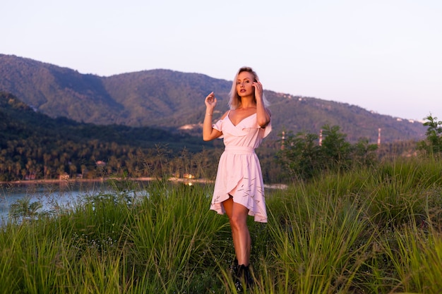 Retrato romântico de uma jovem mulher caucasiana com vestido de verão relaxando no parque na montanha com vista para o mar tropical. Mulher em viagens de férias pela Tailândia Mulher feliz ao pôr do sol