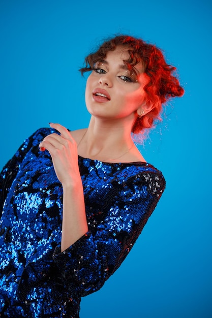Retrato vertical de uma jovem de cabelos encaracolados em fundo azul foto de alta qualidade