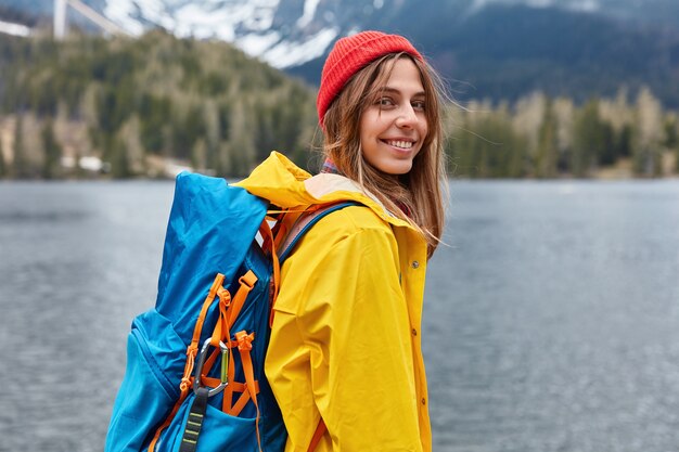 Retrovisor de uma jovem europeia feliz desfrutando de um belo dia sereno, paisagem de paisagem natural e carregando mochila