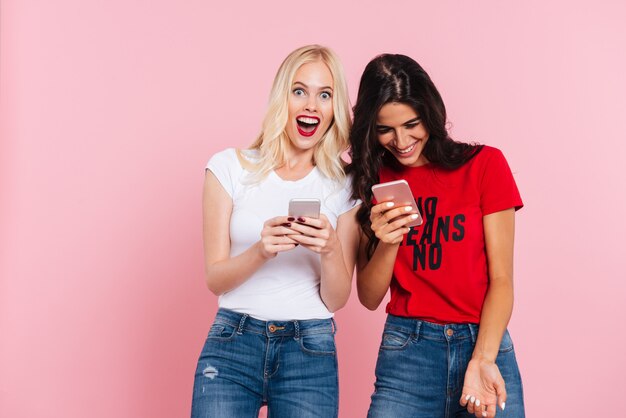 Rindo amigos usando smartphones e sorrindo isolado