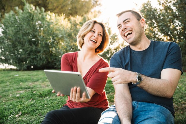 Rindo casal navegando tablet no chão