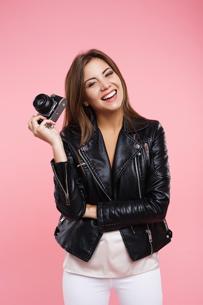 Rindo fotógrafo segurando a câmera de filme antigo, olhando diretamente com o sorriso