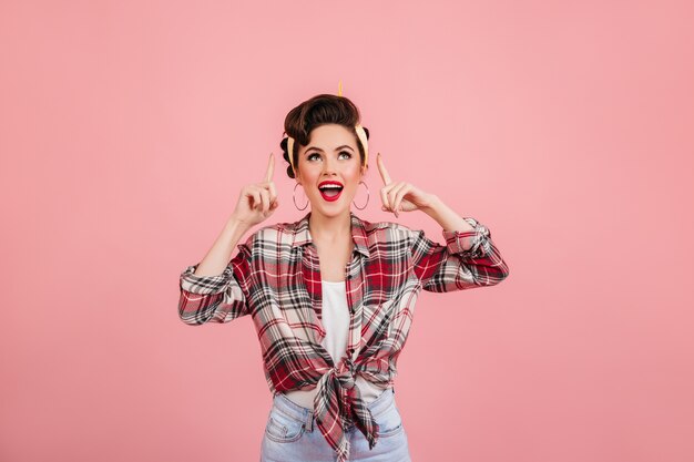 Rindo garota pin-up olhando para cima. Foto de estúdio de emocional jovem de camisa quadriculada.