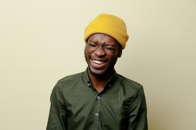 Rindo jovem afro-americano de chapéu vestindo camisa verde isolado no fundo branco