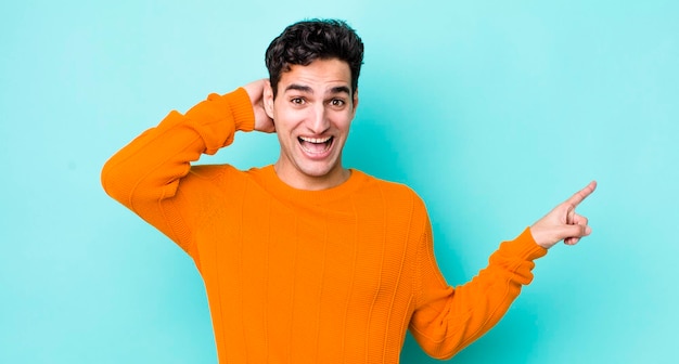 Rindo parecendo feliz positivo e surpreso ao perceber uma ótima ideia apontando para o espaço lateral da cópia