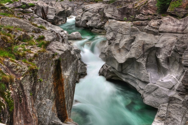 Rio cercado por rochas cobertas de musgos no Valle Verzasca, na Suíça