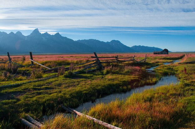 Rio no meio de um campo verde rodeado por uma paisagem montanhosa