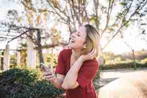 Foto grátis rir mulher com smartphone no parque