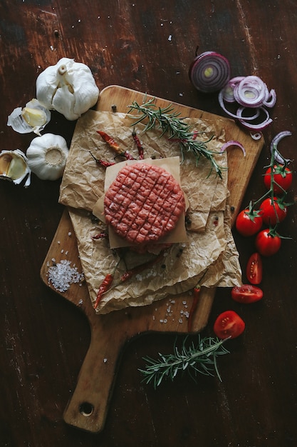 Foto grátis rissóis de hambúrguer de carne crua com ervas e especiarias na placa de ardósia escura