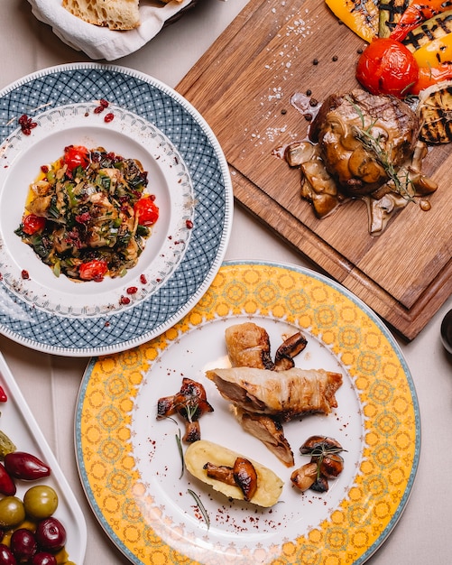 Rocambole de frango vista superior com purê de batatas cogumelos salada de legumes grelhada e carne vermelha com cogumelos e molho em cima da mesa