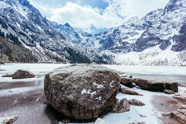 Rochas sobre o lago com montanhas no inverno