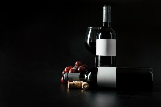 Rolhas e uvas perto de garrafas e copos de vinho