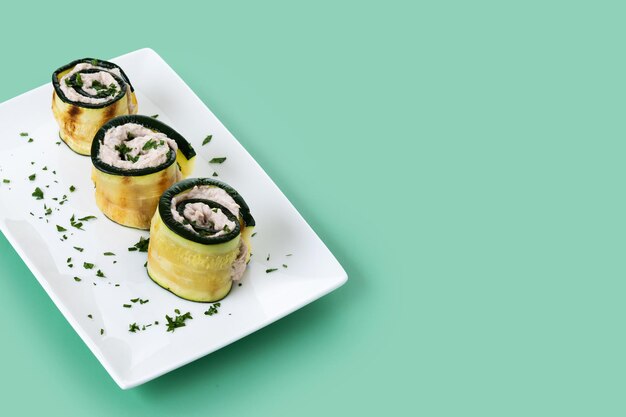 Rolinhos de abobrinha grelhada com atum e cream cheese em fundo verde