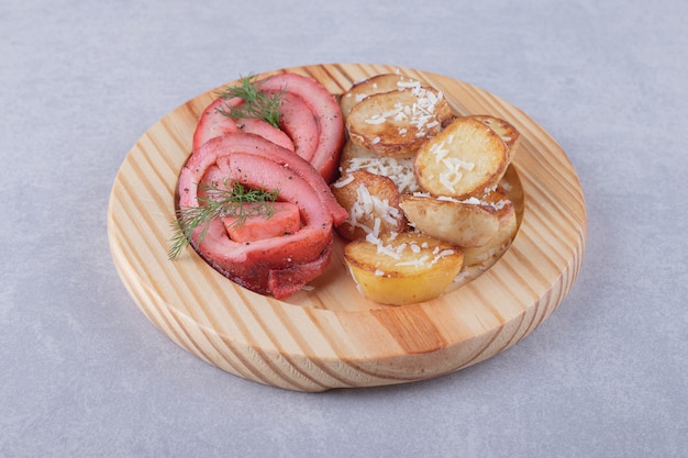 Rolinhos de presunto e batatas fritas em um pedaço de madeira.