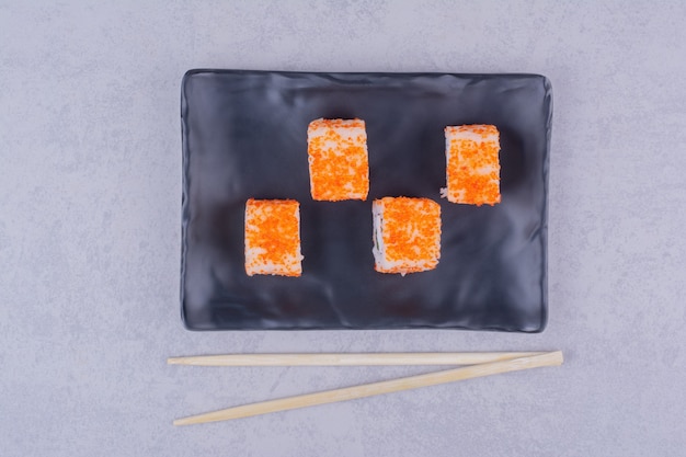 Rolinhos de sushi com salmão em travessas de cerâmica preta