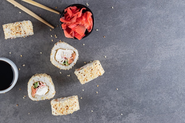 Rolinhos de sushi, molho de soja, wasabi e gengibre em conserva em fundo de pedra.