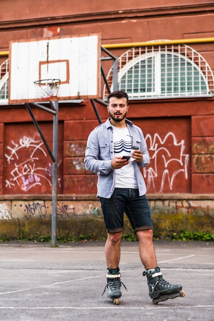 Foto grátis rollerskater masculino usando telefone celular na quadra de basquete