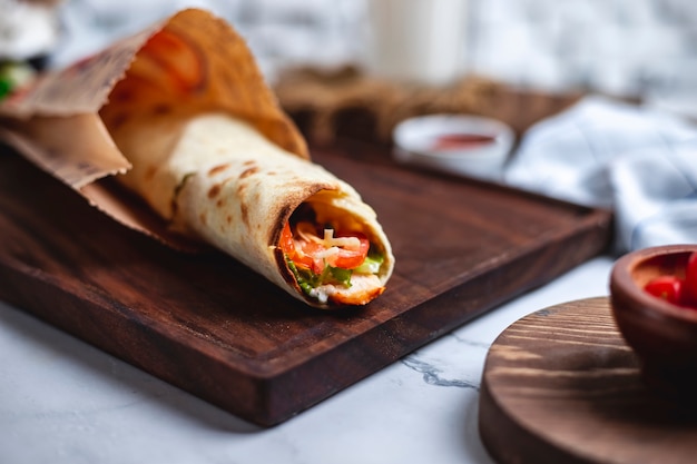 Foto grátis rolo de frango na tábua de madeira tomate alface pimentão queijo vista lateral