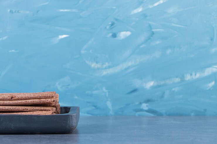 Foto grátis rolo de wafer de chocolate saboroso em uma placa de madeira na superfície de mármore
