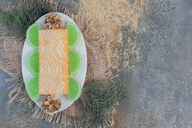 Rolo doce com geléias verdes e pinhas em um prato branco. foto de alta qualidade