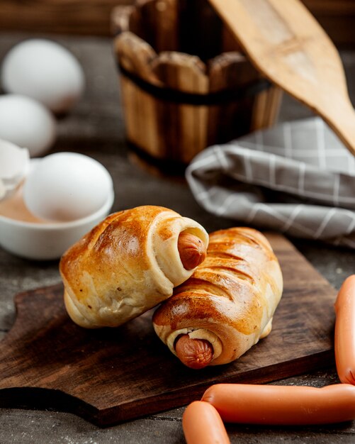 Rolos de pão de salsicha, servidos na tábua de madeira