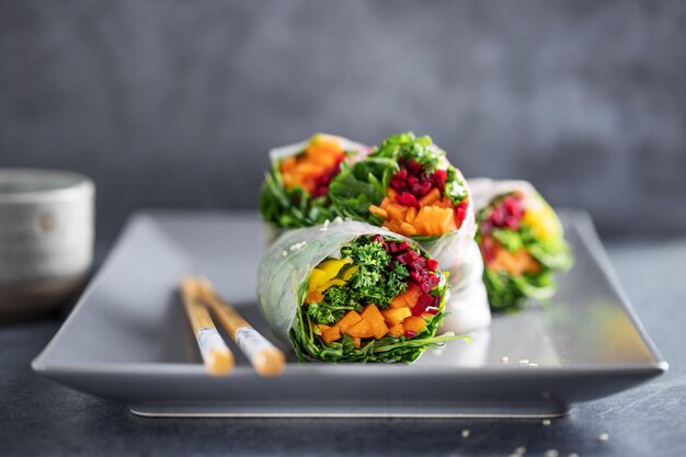 Rolos de papel de arroz vegano com legumes e gergelim servidos no prato pronto para comer