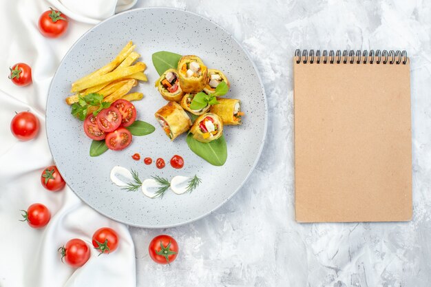 Rolos de patê de vegetais com tomate e batata frita dentro do prato na superfície branca