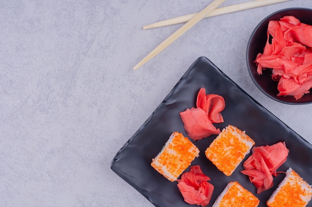 Rolos de salmão da Filadélfia com gengibre vermelho em uma travessa de cerâmica