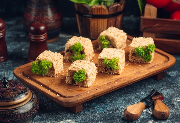 Rolos de sushi com pistache verde em uma placa de madeira.
