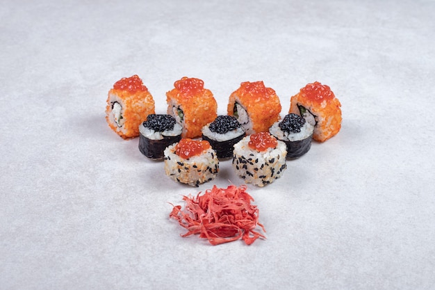 Rolos de sushi maki, alasca e califórnia em fundo branco com gengibre em conserva.