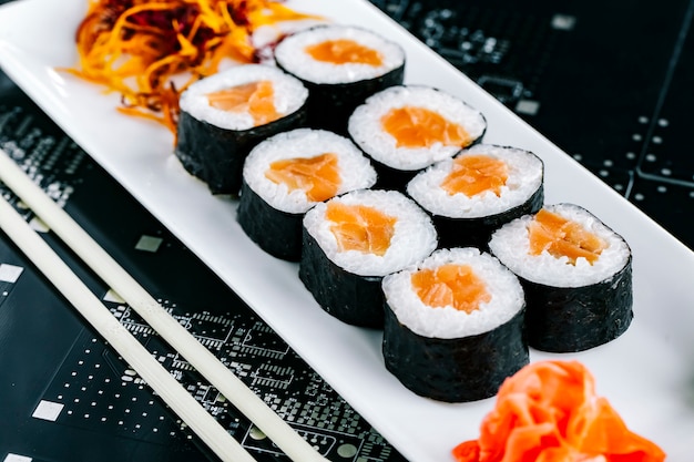 Rolos de sushi Nori com salmão servidos com wasabi de gengibre e cenoura picada