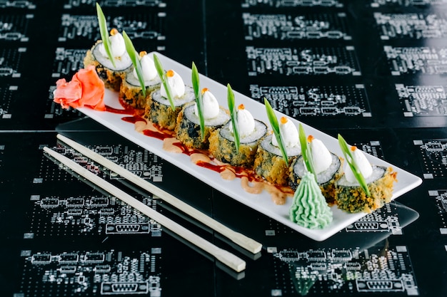 Rolos de sushi quente cobertos com maionese japonesa tobiko vermelho e cebolinha