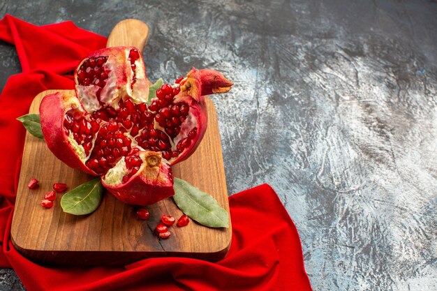 Romã cortada em fatias de frutas vermelhas frescas em uma mesa clara-escura