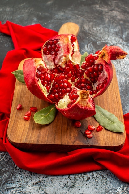 Romã cortada em fatias de frutas vermelhas frescas na mesa claro-escuro frutas vermelhas frescas
