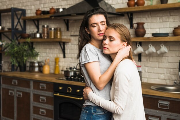 Romântico jovem casal de lésbicas em pé na cozinha