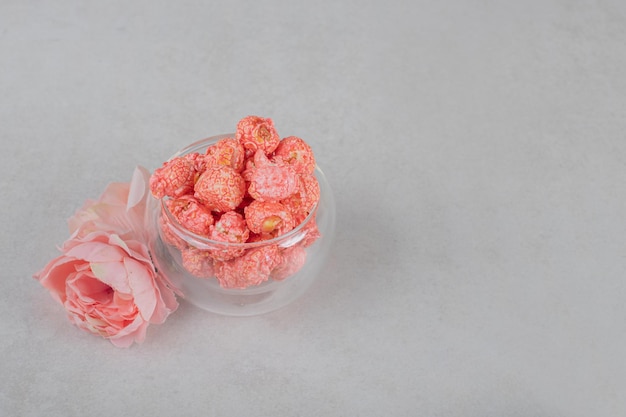 Rosa corola e uma tigela de vidro de pipoca na mesa de mármore.