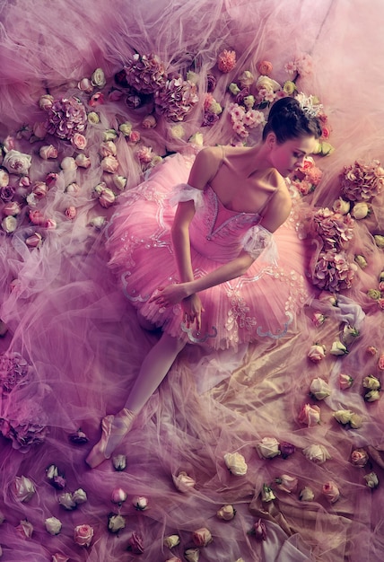 Rosa perfeito. vista superior de uma bela jovem em tutu de balé rosa, rodeada por flores. humor de primavera e ternura à luz coral. conceito de primavera, flor e despertar da natureza.