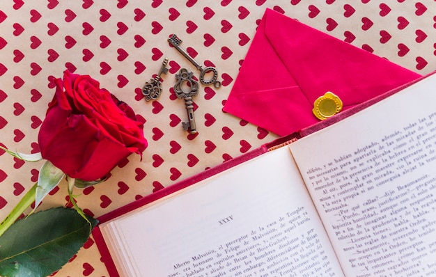 Rosa vermelha com livro e envelope na mesa