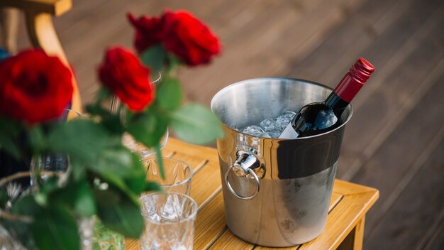 Rosas e garrafa de vinho no balde de gelo na mesa