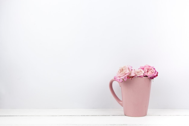 Rosas lindas rosa em caneca de cerâmica em casa