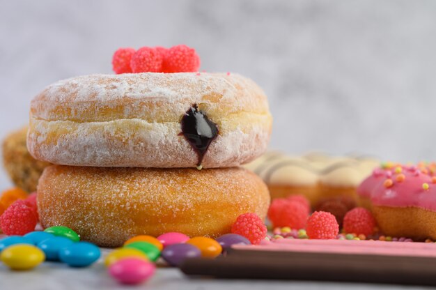 Rosquinhas polvilhadas com açúcar e doces em uma superfície branca.