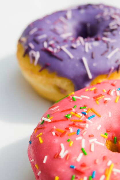 Rosquinhas rosa e roxas com colorido polvilhe em pano de fundo branco