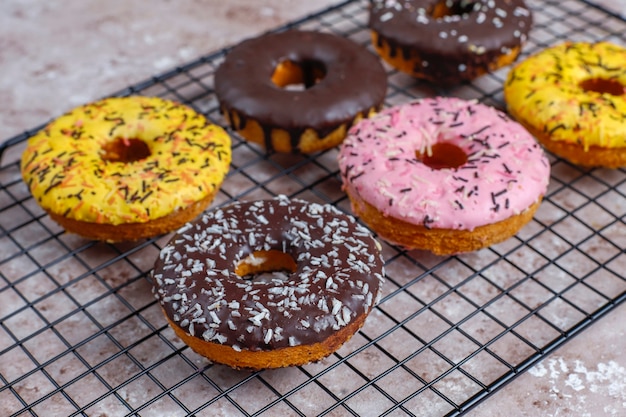 Rosquinhas variadas com cobertura de chocolate, glacê rosa e granulado.