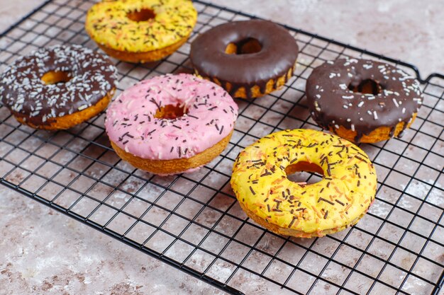 Rosquinhas variadas com cobertura de chocolate, glacê rosa e granulado.