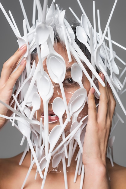 Rosto de mulher asiática sendo coberto por um close-up de plástico branco