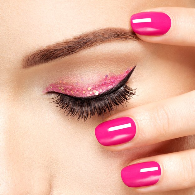 Foto grátis rosto de mulher closeup com unhas rosa perto dos olhos. unhas com manicure rosa