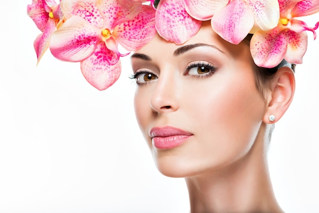 Foto grátis rosto de mulher jovem e bonita com pele saudável e flores cor de rosa - isolado no branco